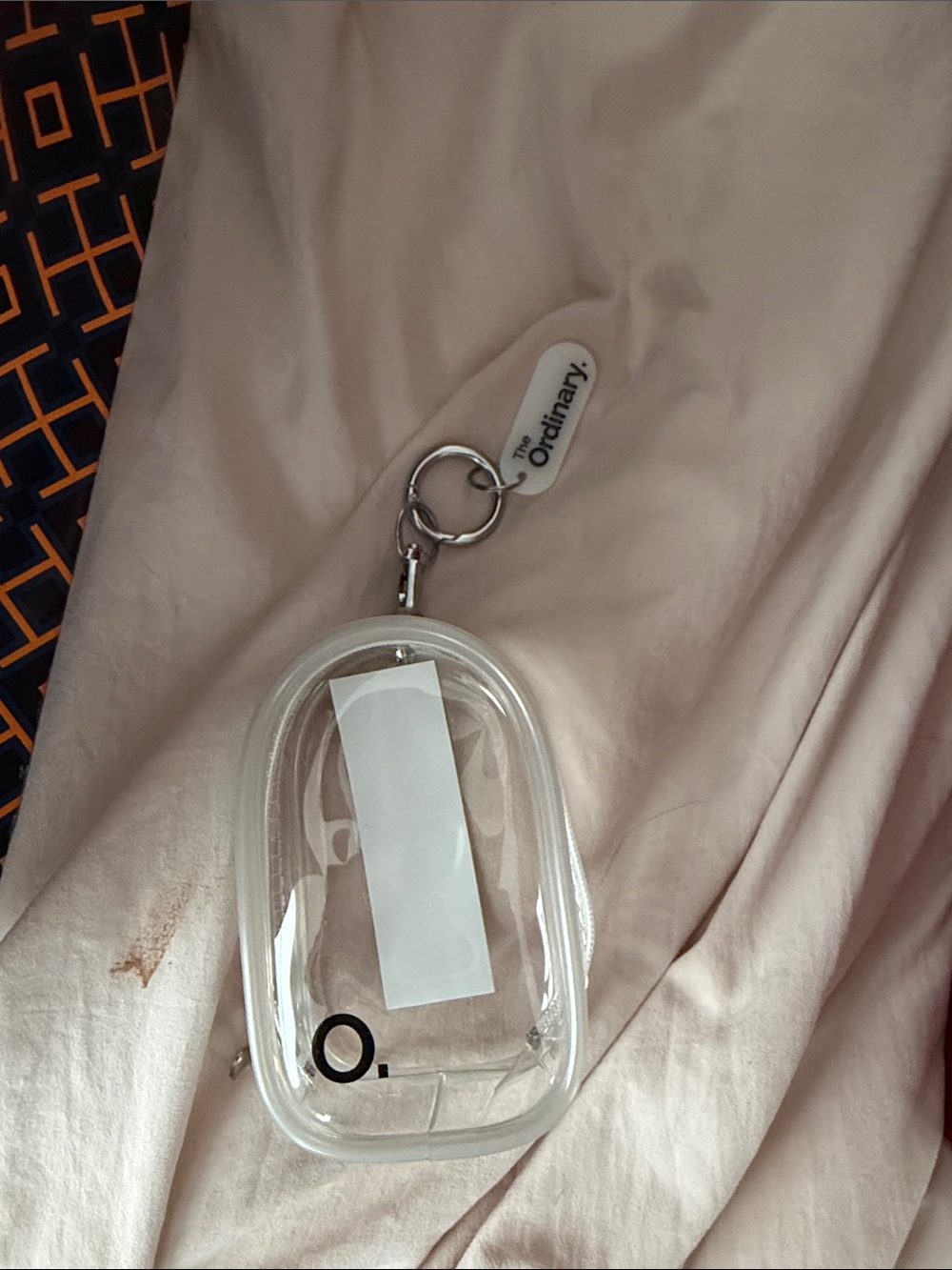 The Ordinary transparent keychain pouch with white tag